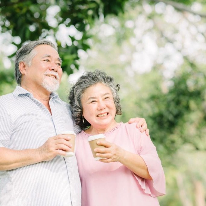 Happy Asian senior older couple drink coffee together outdoor in park